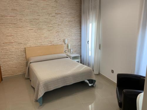 um quarto com uma cama e uma parede de tijolos em Hostal Cervantes em Valdemoro