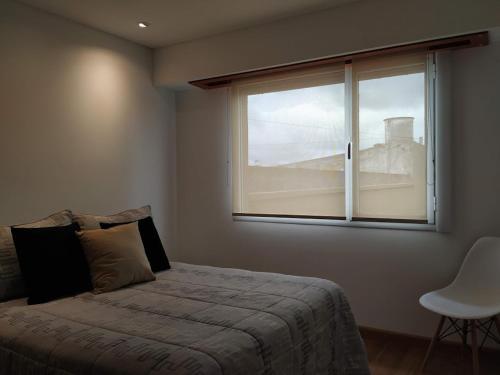 1 dormitorio con cama y ventana en Apartamento 46 en Necochea