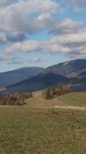 a field with a fence and mountains in the background at Hotel Kačenka in Králíky