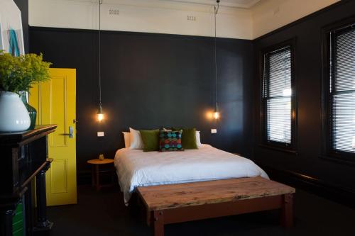 1 dormitorio con cama y puerta amarilla en The Franklin Boutique Hotel en Adelaida