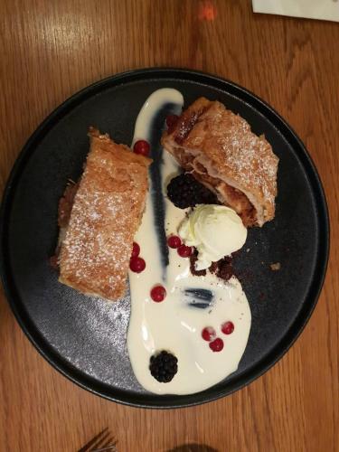 a black plate with two pieces of cake and ice cream at Gorska Reka Guesthouse in Zreče