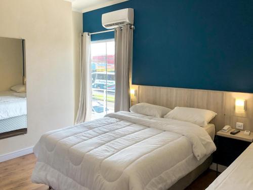 a bedroom with a large bed with a blue wall at Sense Flat Hotel in Araucária