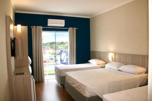 a hotel room with two beds and a window at Sense Hotel Araucária in Araucária