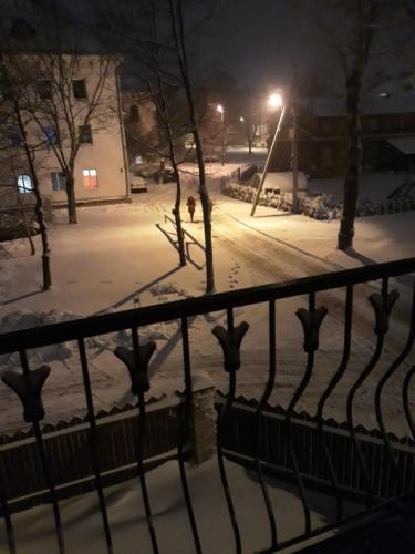 a snow covered street at night with a fence at Centras in Kėdainiai