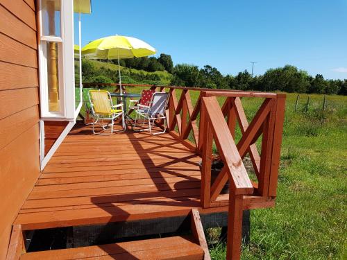 a wooden deck with two chairs and an umbrella at Cabañas Agua Viva in Puerto Montt