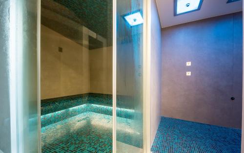 - basen ze szklanym prysznicem w łazience w obiekcie Sporthotel Walliserhof w mieście Unterbäch
