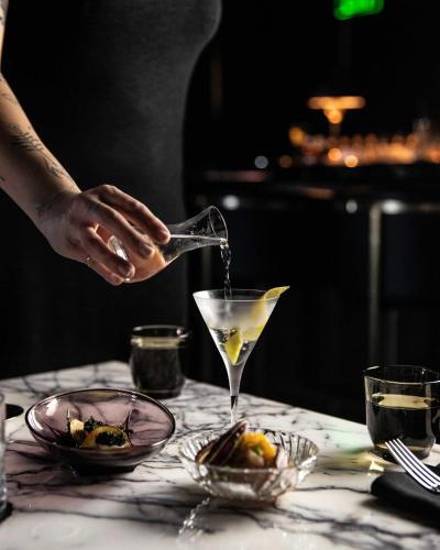 a person pours a drink into a martini glass at The Ramble Hotel in Denver
