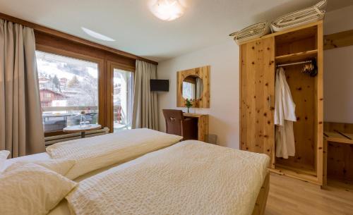 a bedroom with two beds and a window at Sporthotel Walliserhof in Unterbäch