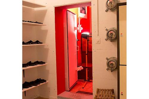a room with a red door and shelves with shoes at Auberge de Bagnes - le backpacker in Bagnes