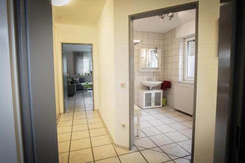 einen Flur eines Badezimmers mit einem Waschbecken und einem Spiegel in der Unterkunft Ferienwohnung Behner in Greven