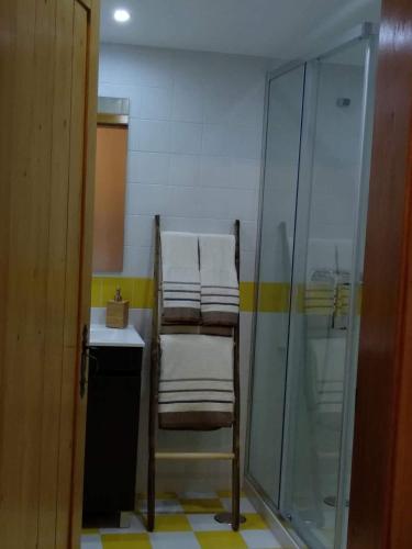 a bathroom with a shower and a stack of towels at Villa Rominha Alvaiázere - Casa do Rancho in Alvaiázere