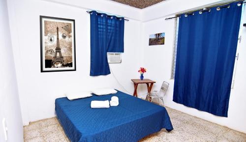 Habitación con cama azul y cortinas azules. en Hotel Europa, en San Miguel