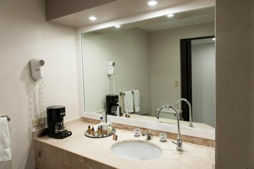a bathroom with a sink and a large mirror at Grand Hotel Tijuana in Tijuana