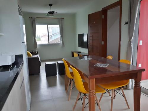 a kitchen with a wooden table and yellow chairs at Beira Mar Village in Pinheira