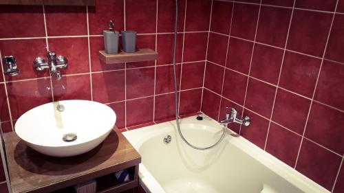 un bagno piastrellato rosso con lavandino e vasca di Apartmán Lucie a Pardubice