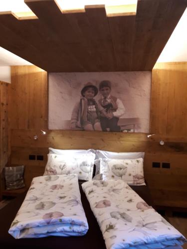 a bedroom with two beds and a picture on the wall at Majon de la nona in Pozza di Fassa