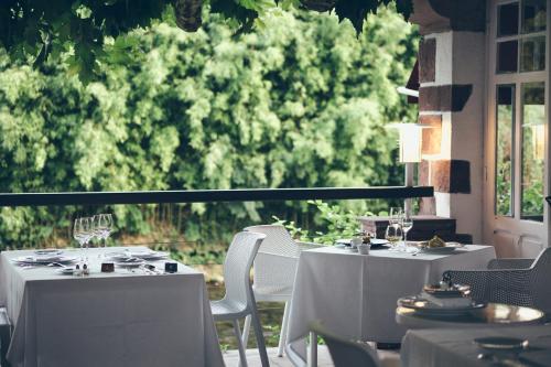 two white tables and chairs on a patio at Hôtel Arcé in Saint-Étienne-de-Baïgorry
