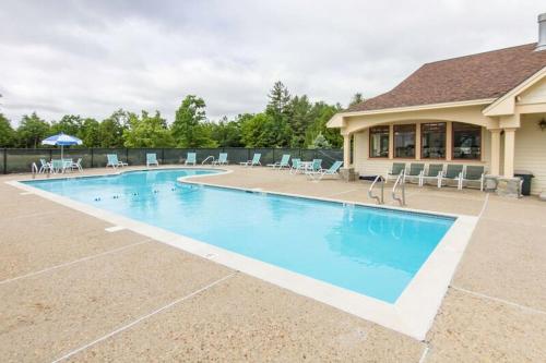 a large swimming pool with chairs and a house at Owl's Nest Resort in Thornton