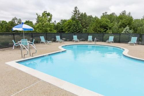 a pool with a table and chairs and an umbrella at Owl's Nest Resort in Thornton