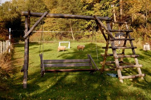 a park bench and two sheep in a field at Dom nad potokiem in Krzyżanów