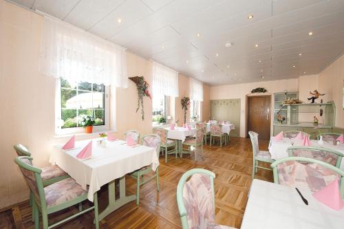 a restaurant with white tables and chairs and pink tables at Hotel Deutsches Haus in Kurort Gohrisch