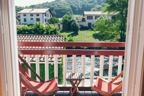 two chairs on a balcony with a view of the river at Hôtel Arcé in Saint-Étienne-de-Baïgorry