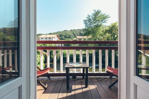 a porch with a table and chairs on a balcony at Hôtel Arcé in Saint-Étienne-de-Baïgorry