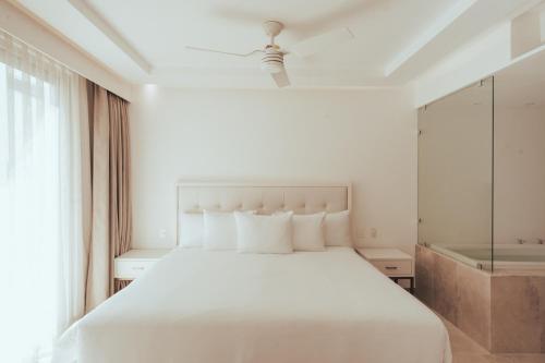 a bedroom with a white bed and a window at Antera Hotel & Residences in Playa del Carmen