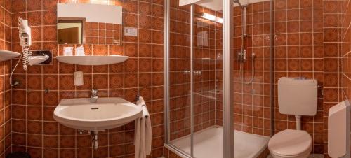 a bathroom with a sink and a toilet and a shower at Hotel Gammelby in Eckernförde