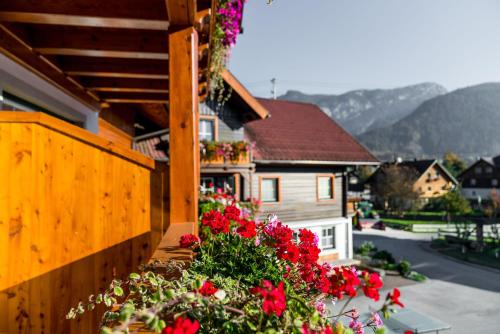 a balcony with red flowers and a house at Linharterhof Appartement in Haus im Ennstal