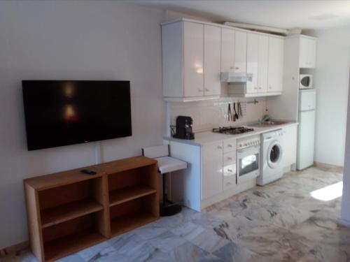 uma cozinha com armários brancos e uma televisão na parede em Casa Sevilla em Valencina de la Concepción