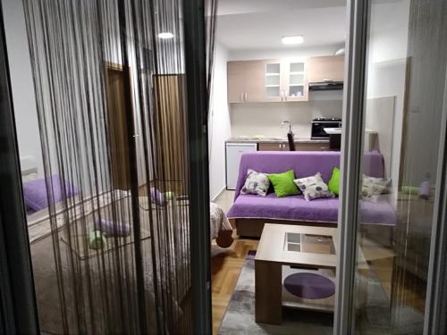sala de estar con sofá púrpura y mesa en Apartman Magdalena, en Trebinje