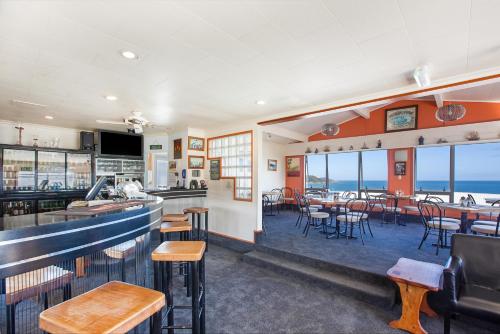 a restaurant with a bar and tables and chairs at Ahipara Bay Motel in Ahipara