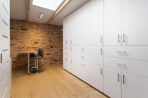 a kitchen with white cabinets and a wooden table at FIFNY Apartment in Poznań