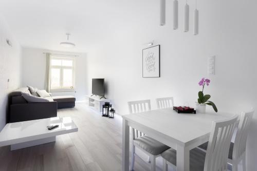 a white living room with a table and a couch at AKURATNY Apartment in Poznań