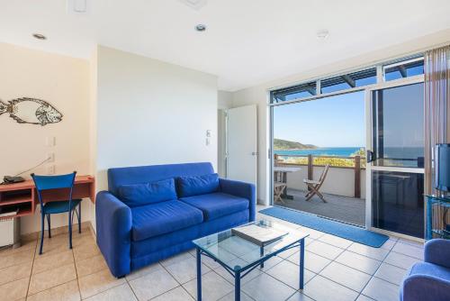a living room with a blue couch and a view of the ocean at Ahipara Bay Motel in Ahipara