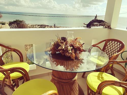 a glass table with a flower arrangement on a balcony at Goldfish Seaside Luxury Houses in Kómi