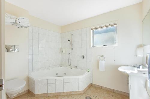 biała łazienka z wanną i toaletą w obiekcie Ahipara Bay Motel w mieście Ahipara