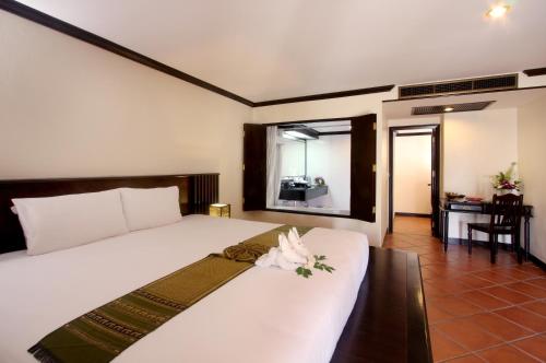 a bedroom with a large white bed with flowers on it at The Front Village - SHA Plus in Karon Beach