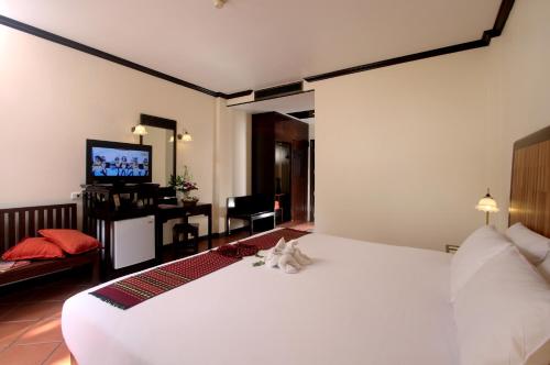 a bedroom with a large white bed and a desk at The Front Village - SHA Plus in Karon Beach