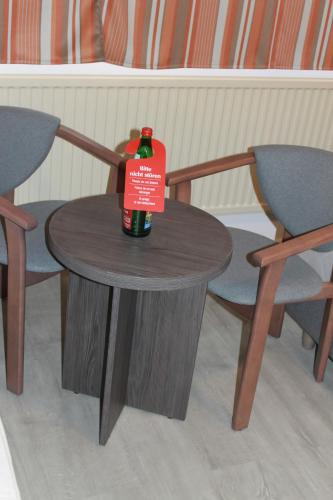a bottle of wine sitting on a table with two chairs at Pionier Hotel Hamburg Wandsbek in Hamburg