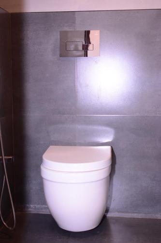 a white toilet in a bathroom with a wall at Alhind Calicut Tower in Kozhikode