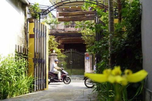 a man riding a motor scooter through an alley at Homestay MINH TÚ in Hue