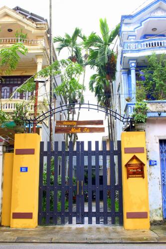 a black fence in front of a building with palm trees at Homestay MINH TÚ in Hue