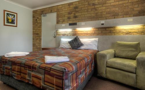 a hotel room with a bed and a chair at True Blue Motor Inn in Rockhampton