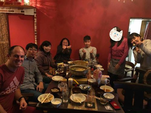 a group of people sitting around a table with food at HappyCloset&WasamonHostel in Kumamoto