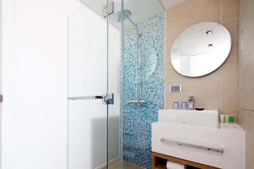a bathroom with a shower and a sink and a mirror at Summit View Kowloon in Hong Kong