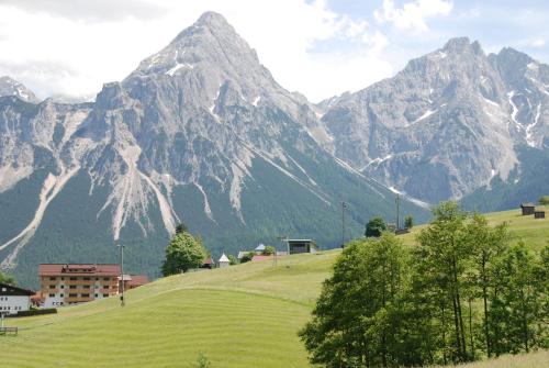 a mountain range with a town on a green hill at Apart Ideal in Lermoos