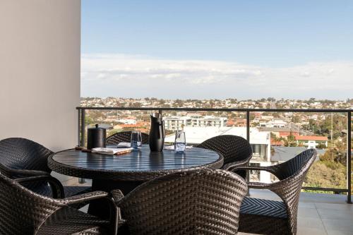 a table and chairs on a balcony with a view at Ramada by Wyndham VetroBlu Scarborough Beach in Perth