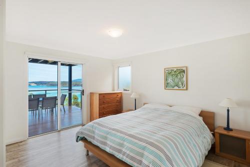 a bedroom with a bed and a view of the ocean at Hillcrest Views of Wagonga in Kianga